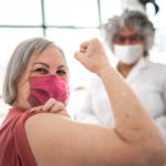 Image: Woman being vaccinated and flexing biceps muscle - wearing face mask